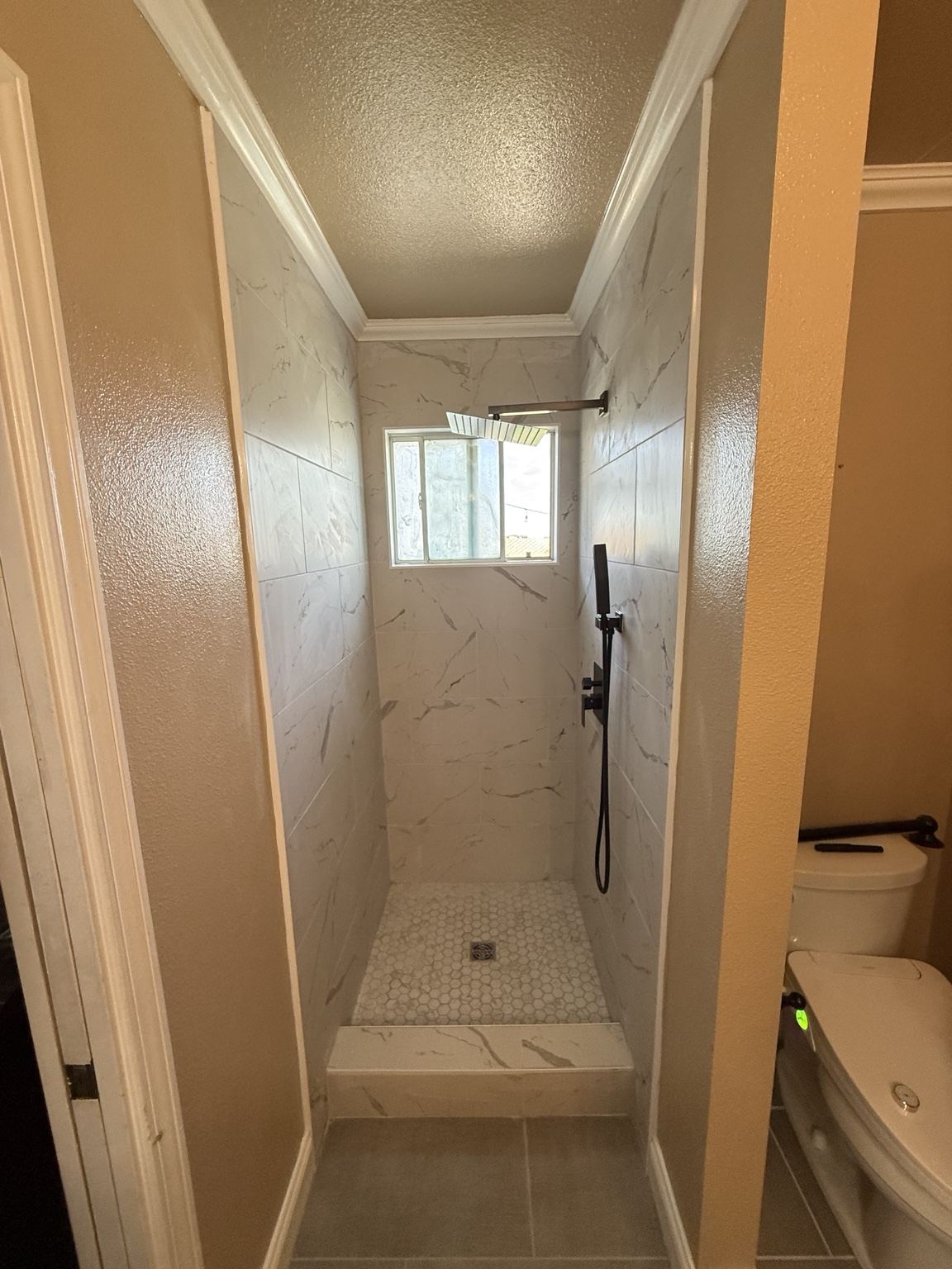 Finished marble-look tile shower with rainfall head