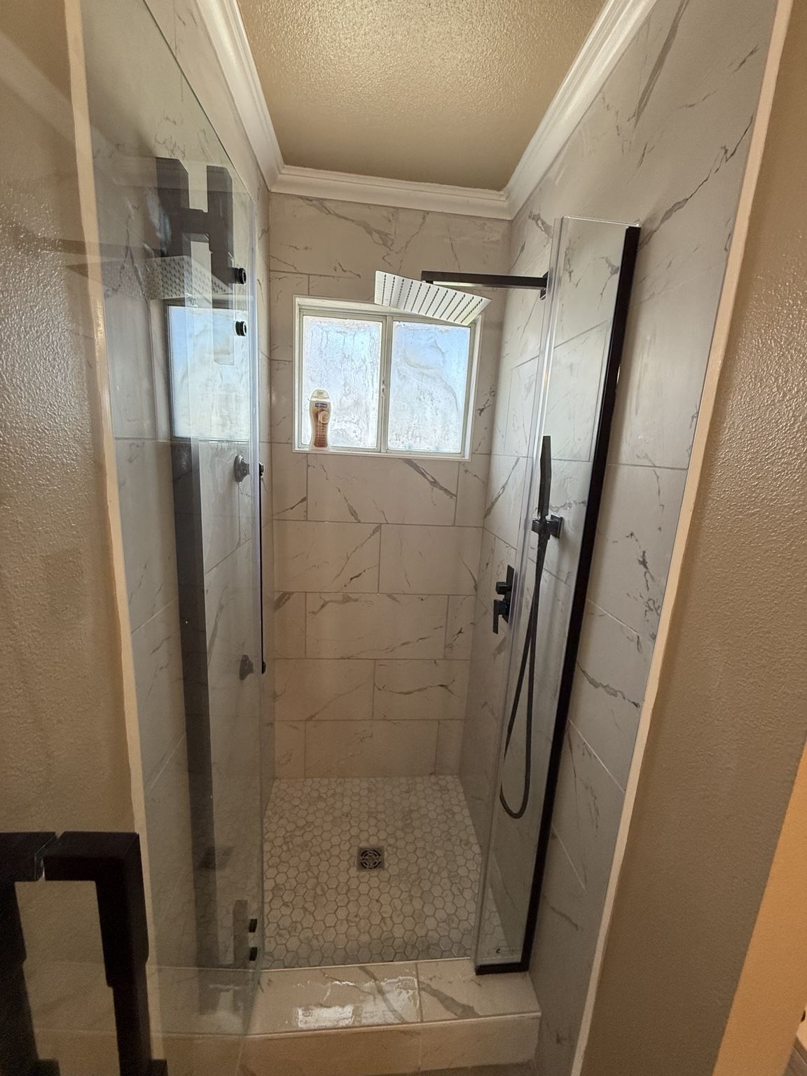 Finished shower with frameless glass door and matte black hardware